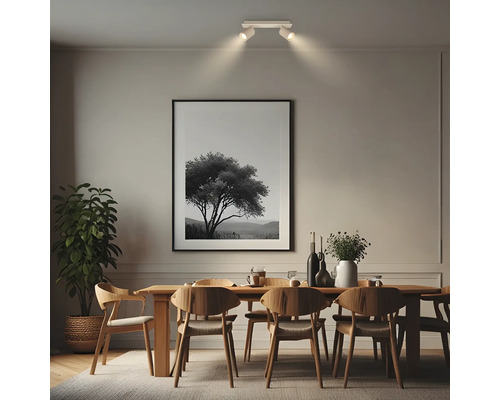 Spot de plafond à deux lampes au-dessus d'une table à manger en bois dans une salle à manger moderne avec tableau et plante verte.