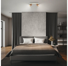 Spot de plafond moderne à 2 lampes en aspect bois au-dessus d'un lit double dans une chambre à coucher au design minimaliste.
