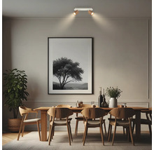 Plafonnier moderne avec deux spots orientables au-dessus d'une table à manger en bois dans une salle à manger lumineuse et ordonnée.