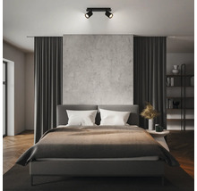 Spot de plafond noir moderne à deux lampes dans une chambre organisée avec mur en béton et lit gris.