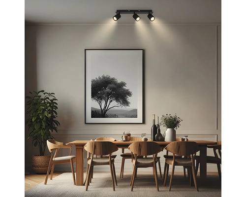 Plafonnier à trois spots dans une salle à manger moderne au-dessus d'une table en bois avec des chaises et un grand tableau.