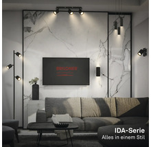 Salon moderne avec éclairage de la série Briloner IDA, comprenant des spots de plafond, un lampadaire et des appliques murales en noir.