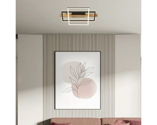 Plafonnier LED moderne avec carrés géométriques en bois et métal dans un salon lumineux au-dessus d'un tableau encadré.