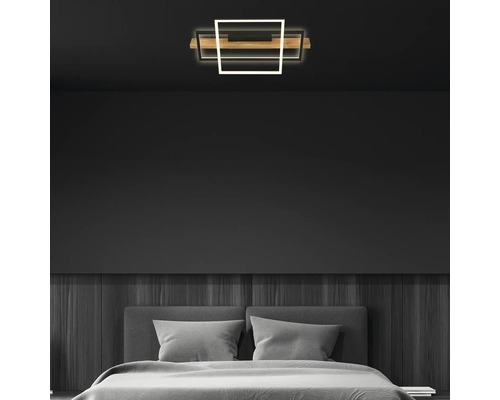 Plafonnier LED moderne dans une chambre à coucher minimaliste avec des murs sombres, des panneaux en bois et un lit gris.