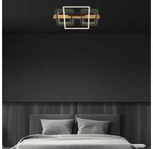 Plafonnier LED à trois éléments carrés et barre en bois dans une chambre à coucher moderne avec des murs sombres.