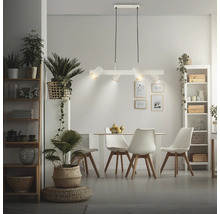 Suspension moderne à 4 lampes blanche au-dessus d'un coin repas de style scandinave avec table claire, chaises et plantes d'intérieur.