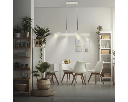 Suspension moderne à 4 lampes blanche au-dessus d'un coin repas de style scandinave avec table claire, chaises et plantes d'intérieur.