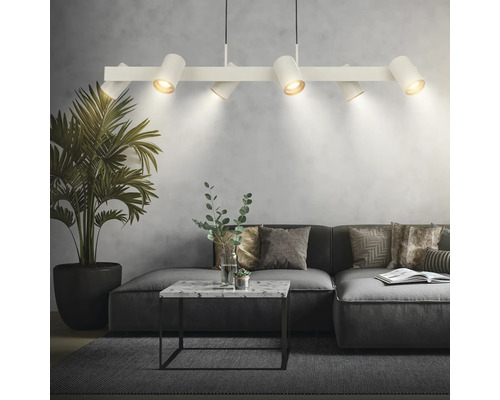 Suspension blanche moderne avec six spots réglables au-dessus d'un canapé gris dans un salon avec table en marbre et plante d'intérieur.
