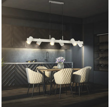 Suspension moderne avec six spots réglables au-dessus d'une table à manger en bois avec des chaises capitonnées dans une cuisine sombre.