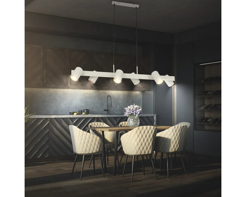 Suspension moderne avec six spots réglables au-dessus d'une table à manger en bois avec des chaises capitonnées dans une cuisine sombre.
