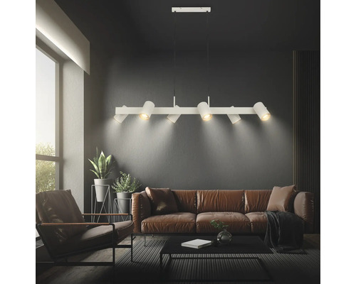 Suspension moderne en métal avec six spots orientables au-dessus d'un canapé dans un salon.