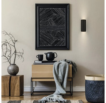 Intérieur moderne avec applique noire, tableau abstrait, buffet en bois, plaid gris, vase avec branches et panier tressé.