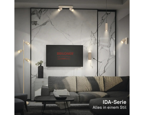 Salon moderne avec spots de plafond, appliques et lampadaire de la gamme Briloner IDA et Briloner Logo sur le moniteur.