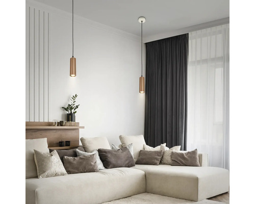 Salon moderne avec un grand canapé d'angle et deux suspensions cylindriques en métal au-dessus du coin salon.