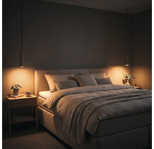 Chambre à coucher moderne avec lit rembourré, deux tables de chevet en bois et lampes suspendues avec une lumière chaude.