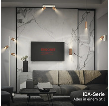 Salon moderne avec luminaires Briloner série IDA : spots de plafond, suspension, applique et lampadaire devant un mur en marbre.