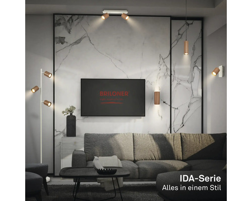 Salon moderne avec luminaires Briloner série IDA : spots de plafond, suspension, applique et lampadaire devant un mur en marbre.