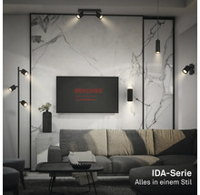 Salon moderne avec des luminaires en métal noir de la série Briloner IDA devant un mur en marbre clair avec canapé et table basse.