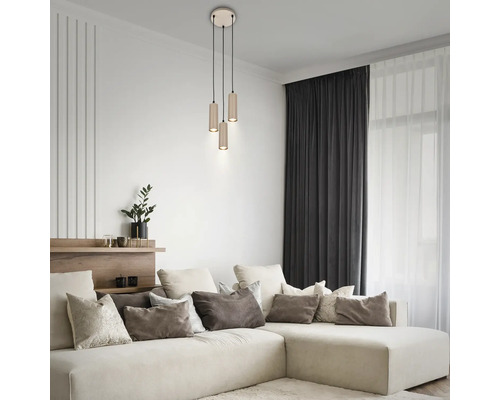 Salon moderne avec suspension à 3 lampes, abat-jours cylindriques et canapé d'angle avec coussins décoratifs.