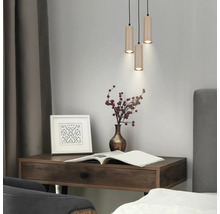 Bureau moderne en bois foncé avec suspension triple, vase avec baies, cadre photo et livre ouvert.