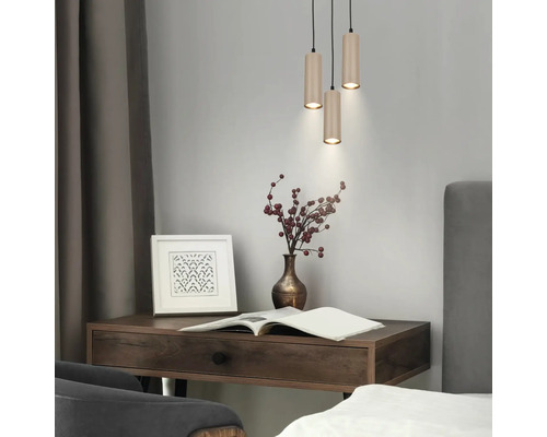 Bureau moderne en bois foncé avec suspension triple, vase avec baies, cadre photo et livre ouvert.
