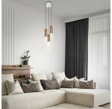 Suspension à trois lampes avec abat-jour cylindriques en métal dans un salon moderne et lumineux avec canapé d'angle et coussins décoratifs.