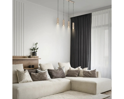 Suspension à 4 lampes avec abat-jour cylindriques en bois dans un salon moderne et lumineux au-dessus d'un grand canapé d'angle.
