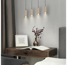 Suspension à quatre lampes avec abat-jour cylindriques aspect bois au-dessus d'un bureau en bois dans une pièce moderne.