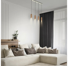 Suspension à quatre lampes avec abat-jour cylindriques en bois dans un salon moderne au-dessus d'un canapé d'angle de couleur crème.
