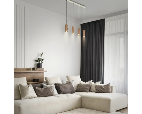 Suspension à quatre lampes avec abat-jour cylindriques en bois dans un salon moderne au-dessus d'un canapé d'angle de couleur crème.