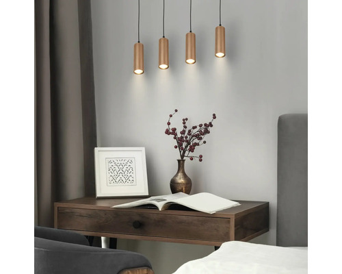 Quatre suspensions cylindriques avec une finition nervurée au-dessus d'un bureau en bois avec un livre, un vase et un cadre dans une pièce moderne.