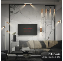 Salon moderne avec lampes en métal de la série IDA de Briloner, canapé gris et mur aspect marbre. Briloner Logo sur le téléviseur.