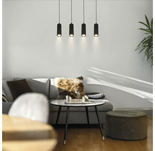 Salon moderne avec canapé gris, table ronde blanche et quatre suspensions cylindriques noires.