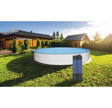 Piscine ronde blanche dans un jardin ensoleillé avec un chauffage de piscine au premier plan sur la pelouse.