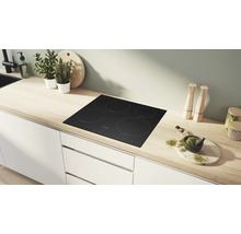Moderne Küche mit schwarzem Bosch Induktionskochfeld mit vier Zonen, eingelassen in eine helle Arbeitsplatte aus Holz mit weißen Unterschränken.