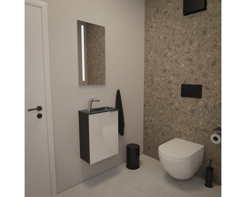 Moderne Gäste-Toilette mit Wand-Toilette, kompaktem Waschtisch und beleuchtetem Spiegel. Akzentwand in Terrazzo-Optik und schwarze Badaccessoires.