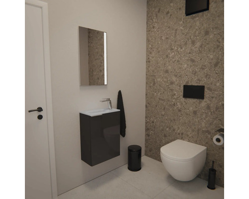 Moderne Gäste-Toilette mit wandhängender Toilette, kleinem Unterschrank in Anthrazit, Spiegel mit Beleuchtung und Fliesen in Steinoptik.