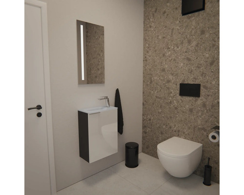 Moderne Gäste-Toilette mit Waschtischunterschrank, beleuchtetem Spiegel, Wand-Toilette und schwarzen Accessoires vor Fliesen in Steinoptik.