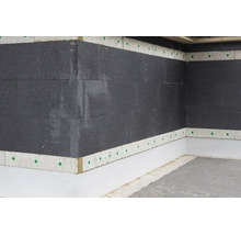 Mur extérieur avec panneaux isolants sombres et bandes de finition claires, fixés avec des chevilles pour isolant sur un angle de bâtiment.