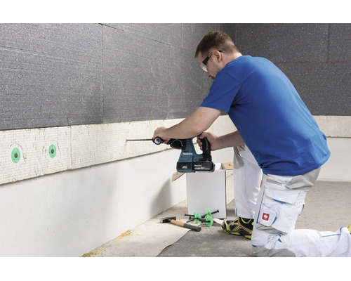 Une personne utilise un perforateur sans fil Makita pour percer un panneau d isolation murale.