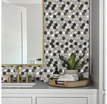 Badezimmer-Szene mit hexagonalem Mosaik-Fliesenspiegel in Stein- und Metalloptik, kombiniert mit goldfarbener Armatur und hellem Waschtisch.