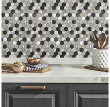 Küchenrückwand mit Hexagon-Mosaikfliesen in Metall- und Steinoptik über einer hellen Arbeitsplatte in einer modernen Küche.