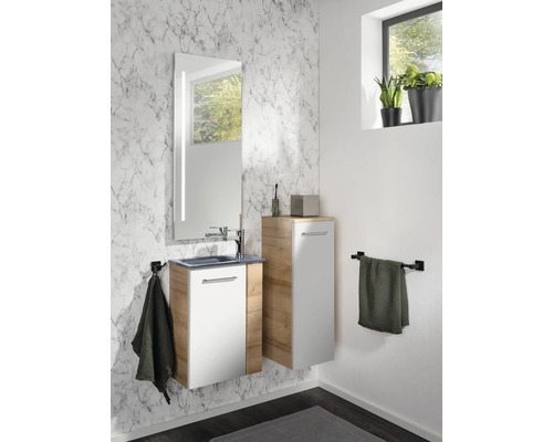Modernes Badezimmermöbel-Set mit Waschtischunterschrank in Weiß und Holzoptik, passendem Hochschrank und beleuchtetem Spiegel vor Marmorwand.