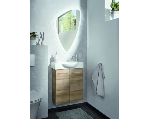Ensemble salle de bains moderne avec meuble sous-lavabo aspect bois, lavabo en céramique et miroir asymétrique avec éclairage.