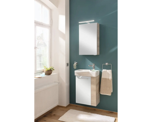 Ensemble de salle de bains avec meuble sous-lavabo blanc et bois, lavabo en céramique et armoire de toilette éclairée.