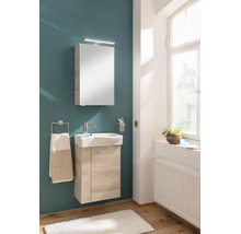 Salle de bain moderne avec meuble sous-lavabo en bois clair, lavabo en céramique blanche, armoire de toilette avec éclairage et porte-serviettes.