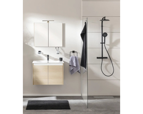 Modernes Badezimmer mit Waschtischunterschrank in Eichenoptik, Spiegelschrank und schwarzer Duscharmatur hinter einer Glastrennwand.