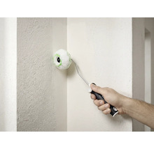 Un petit rouleau d'angle rond est utilisé pour peindre le coin intérieur d'un mur blanc texturé.