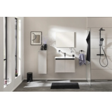 Modernes, helles Badezimmer mit weißem Waschtischunterschrank, Hochschrank, Spiegel und schwarzem Duschsystem mit Regenduschkopf.