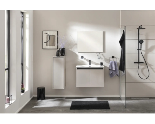 Modernes, helles Badezimmer mit weißem Waschtischunterschrank, Hochschrank, Spiegel und schwarzem Duschsystem mit Regenduschkopf.
